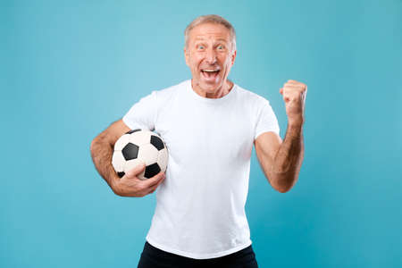 Mature man posing with soccer ball on blue backgroundの写真素材
