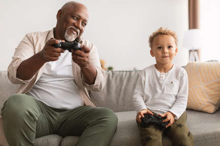 Black Grandfather And Grandson Playing Videogames Having Fun At Homeの写真素材