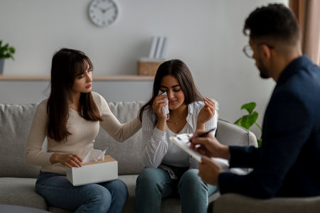 Young arab woman crying, her partner comforting her on session with marital counselor. Homosexual marriages problemsの写真素材