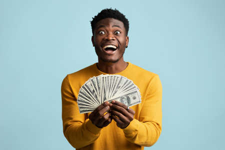 Lucky african american guy holding bunch of moneyの写真素材