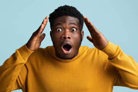Shocked black man looking at camera, gesturing on blueの写真素材