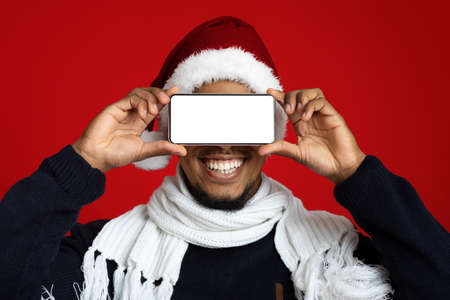 Cheerful african american man covering eyes with smartphoneの写真素材