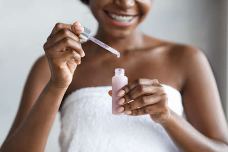Unrecognizable black woman holding bottle with beauty productの写真素材