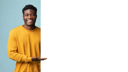 Smiling african american man standing by huge blank advertising board