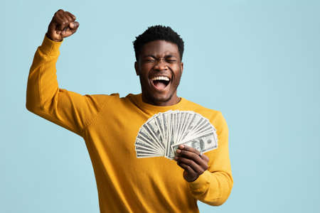 Emotional black man with bunch of cash raising hand up