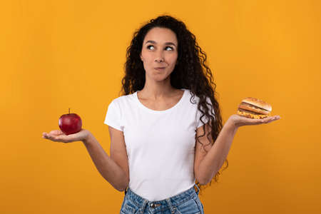 Portrait of Smiling Latin Lady Holding Apple And Burger