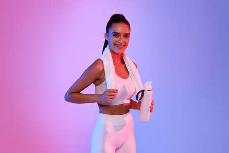 Sporty Lady Holding Bottle Of Water Posing On Neon Backgroundの写真素材