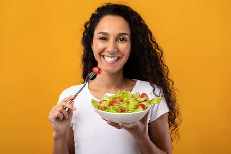 Portrait of Smiling Latin Lady Holding Plate With Saladの写真素材