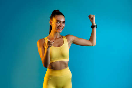 Fitness Lady Showing Biceps Pointing Finger At Camera, Blue Backgroundの写真素材