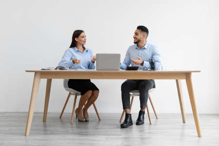 Portrait Of Smiling Colleagues Talking Sitting At Desk