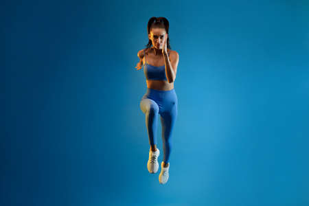 Front-View Of Motivated Sportswoman Running Over Blue Background, Full Lengthの写真素材