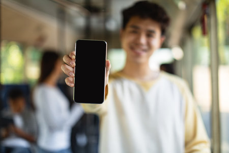 Asian man showing black empty smartphone screen, closeupの写真素材