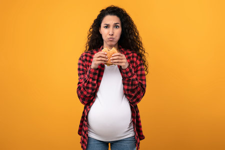 Pregnant Lady Holding Eating Burger At Studioの写真素材