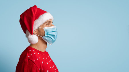 Profile Portrait Of Young Man In Santa Hat And Medical Face Maskの写真素材