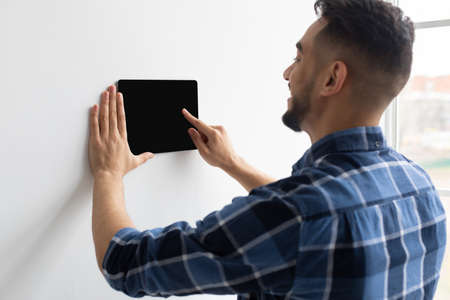 Happy man using smart wall home control systemの写真素材