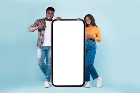 Couple showing white empty smartphone screen leaning on display