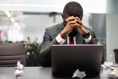 Tired black manager suffering from burnout, working on laptop