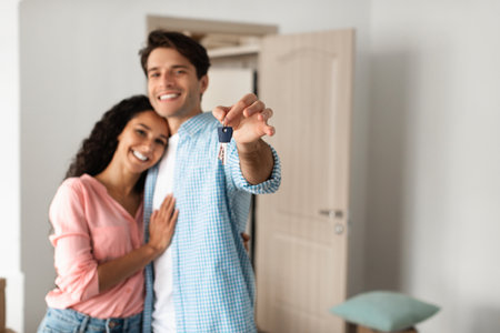 Happy man and woman posing with keys on moving dayの写真素材