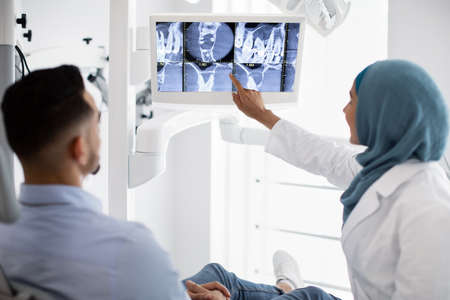Root Canal Treatment. Muslim Female Dentist Showing Xray Picture On Digital Monitorの写真素材