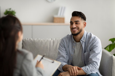 Effective psychotherapy. Happy middle eastern man talking to his psychologist, sharing therapy results with counselorの写真素材