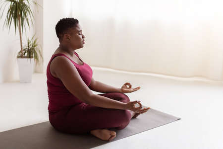 Relaxed fat black lady in sportswear having yoga practice, panoramaの写真素材