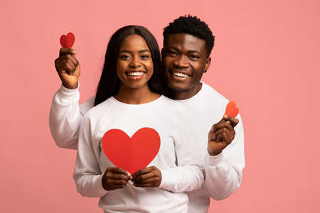 Happy african american lovers posing with red heartsの写真素材