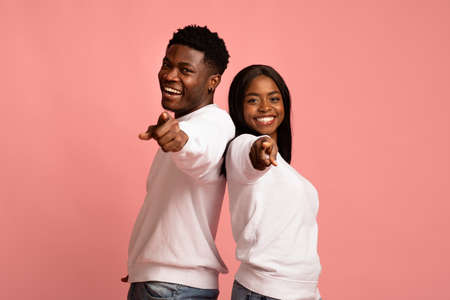 Happy african american man and woman indicating at cameraの写真素材