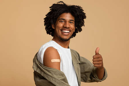 Be Vaccinated. African Guy With Adhesive Bandage On Arm Showing Thumb Up