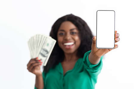 Cheerful black woman showing cellphone with empty screen and cashの写真素材