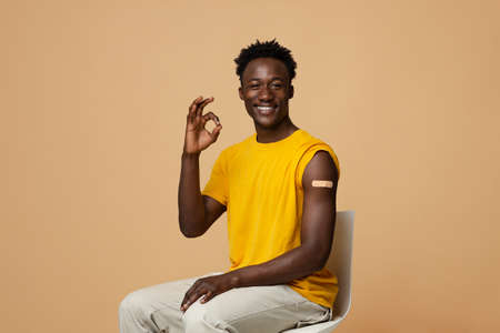 Vaccinated Black Guy With Adhesive Bandage On Arm Showing Ok Gesture
