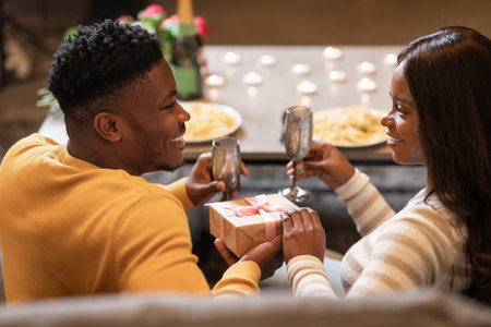 Black Boyfriend Surprising Girlfriend Giving Gift Box Celebrating Valentine Indoorの写真素材