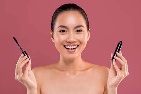 Beautiful asian woman holding mascara on purple backgroundの写真素材