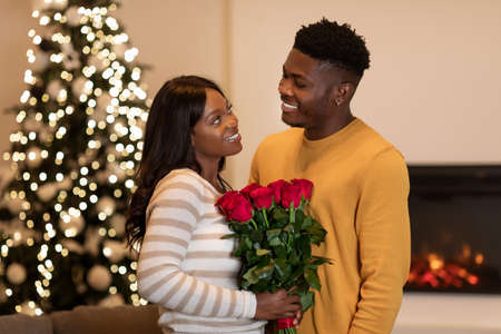 Black Boyfriend Congratulating Wife On New Year Giving Flowers Indoorの写真素材