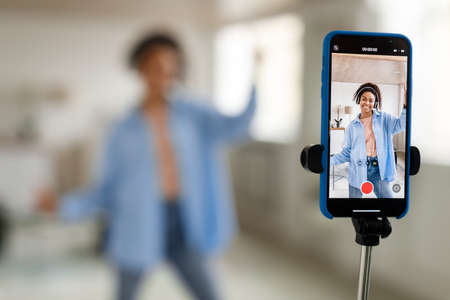 Cheerful black woman filming video on cellphoneの写真素材