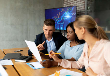 Portrait Of Multiethnic Colleagues Discussing Financial Reports During Meeting In Modern Office