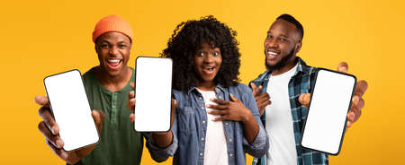 Three excited black people showing smartphones with white blank screen, mockup