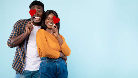 Young Black Couple Covering Eyes With Red Paper Hearts, Panorama