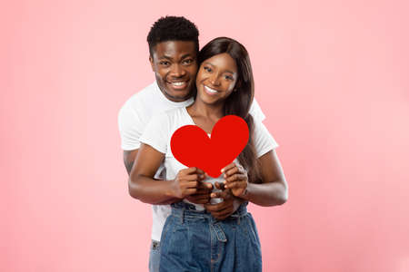 Young Romantic Black Couple Hugging And Holding Red Paper Heart