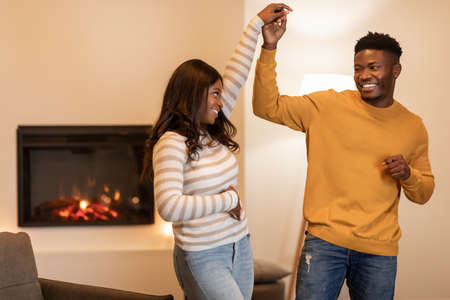 African American Spouses Dancing Near Fireplace Celebrating Holiday At Home