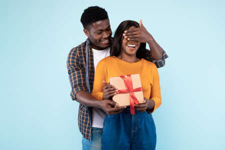 Happy black man making surprise for his woman giving boxの写真素材