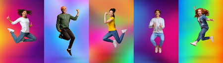 Expressing joy and happiness. Full length of energetic diverse young people jumping over colorful neon backgroundsの写真素材