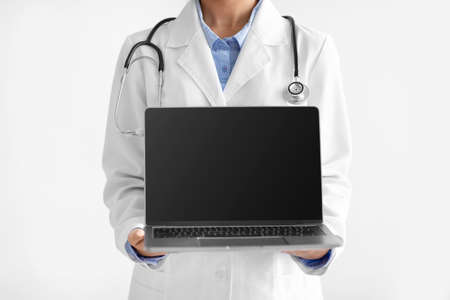 Young indian female doctor in uniform shows computer with empty screen isolated on white background, unrecognizableの写真素材