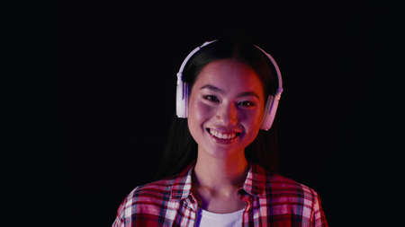 Portrait Of Happy Young Asian Woman Listening Music In Wireless Headphonesの写真素材