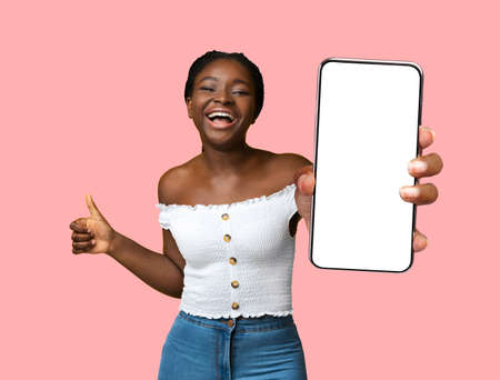 Happy black woman holding smartphone with empty screenの写真素材