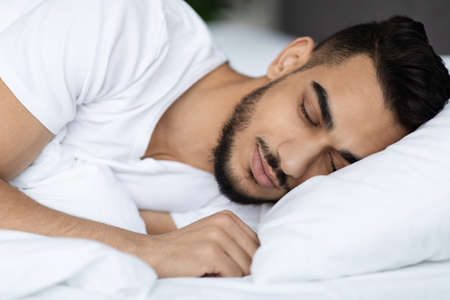 Closeup Shot Of Handsome Young Arab Man Sleeping In Comfortable Bedの写真素材