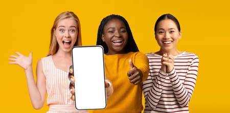 Pretty multiracial ladies posing with modern smartphone, mockupの写真素材