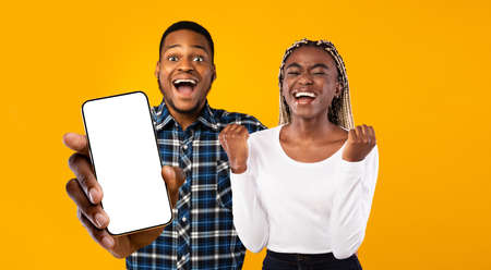 Emotional african american lovers showing cellphone with empty screenの写真素材