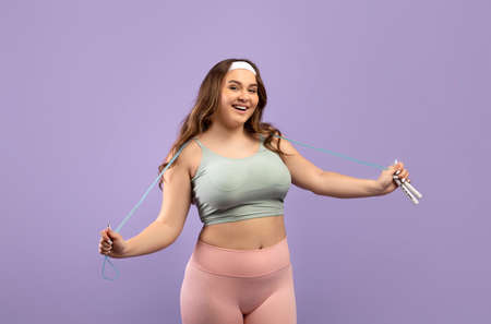 Satisfied funny millennial european woman plus size in sports uniform with skipping rope ready to trainingの写真素材