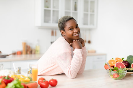 Happy young african american female blogger look at camera in scandinavian kitchen interior with...