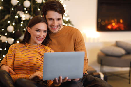 Smiling young couple using laptop at home